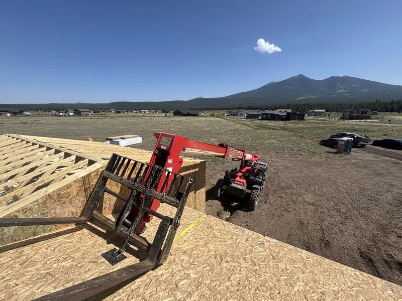 Framing stage with a crane on site and San Francisco Peaks in the background